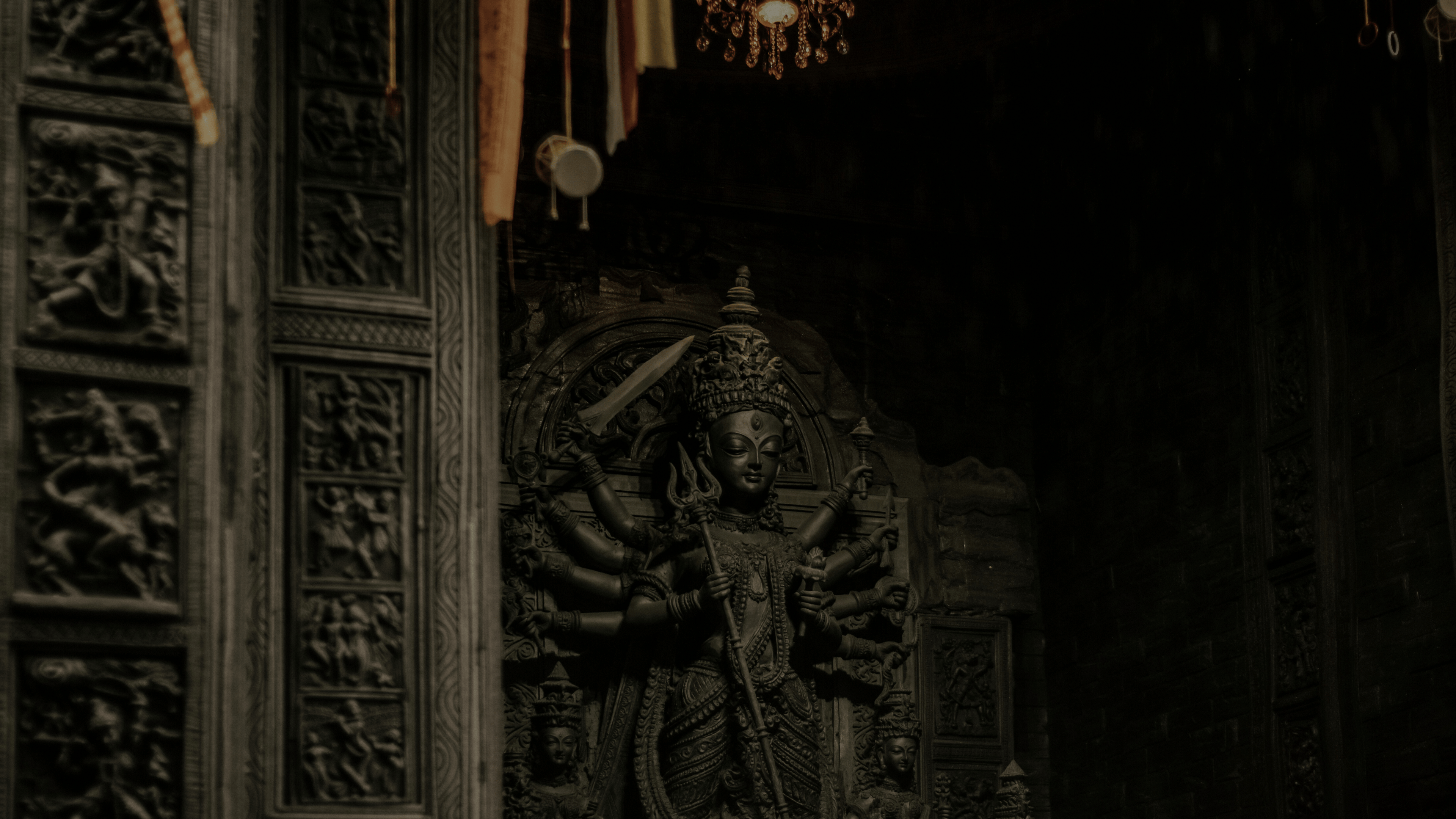 Statue of Ma Durga figure with a headdress in a dark, ornate setting