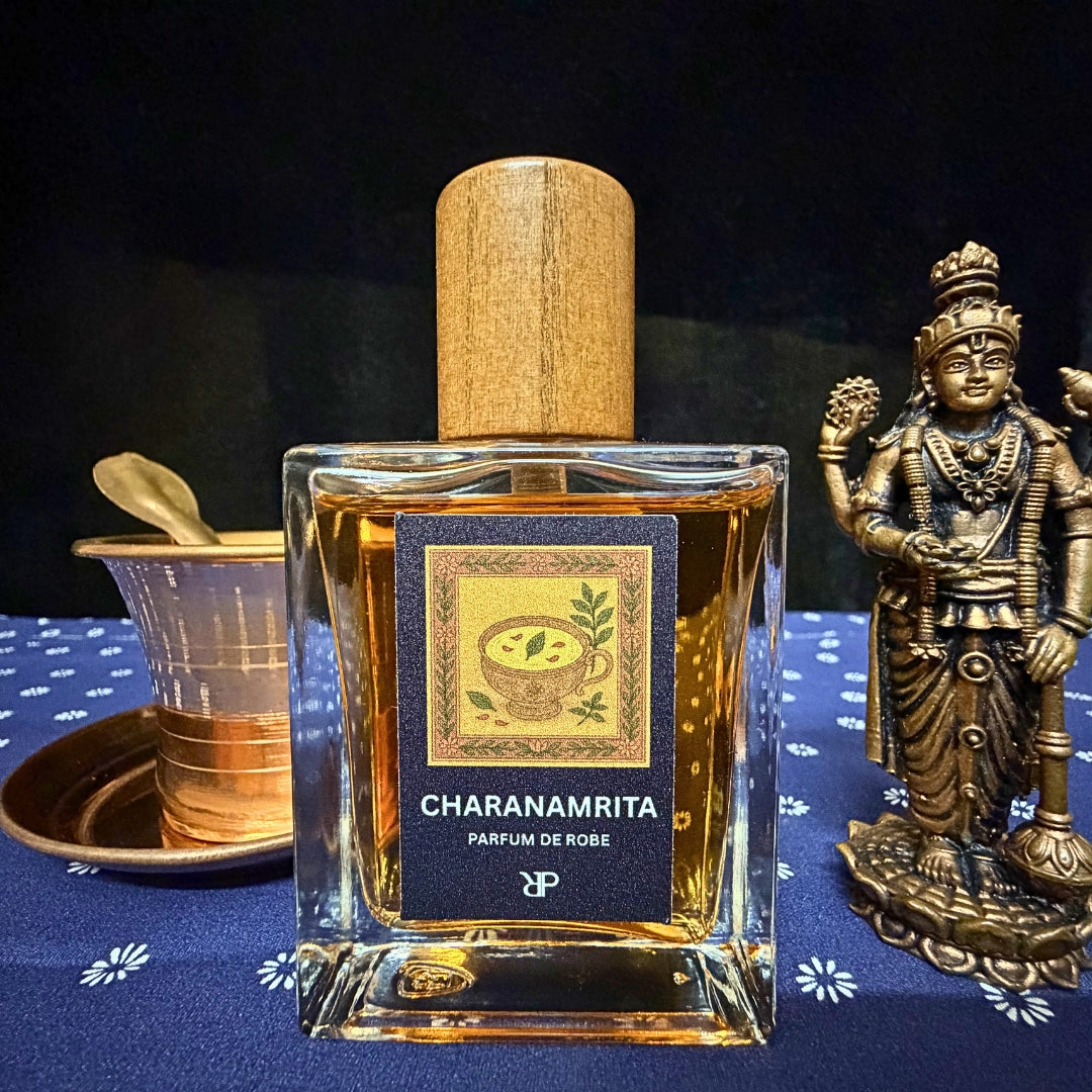 Fragrance bottle labeled 'Charanamrita' with a wooden cap on a dark background