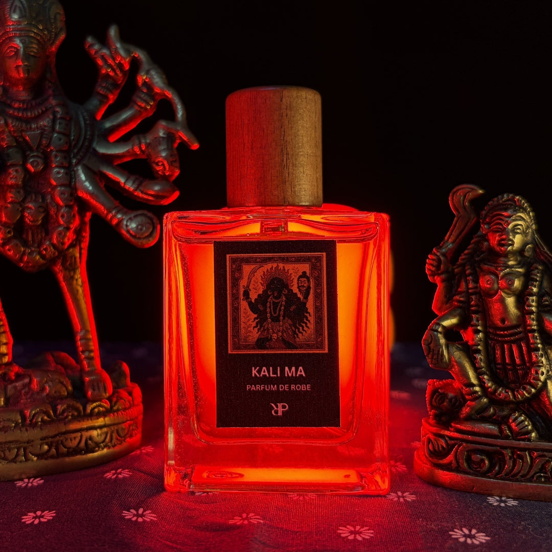 Parayan O Rakkhoshgon kali Ma parfum de Robe fragrance bottle against a red light and idols of Kali Ma in the backdrop